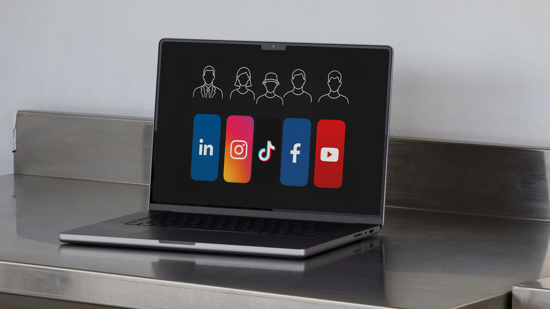 Silberner Laptop auf Metallablage steht aufgeklappt. Zu Sehen ist der Monitor des Laptops, auf dem ist eine Grafik zu erkennen, die die Social Media Plattform Logos von Linkedin, Instagram, TikTok, Facebook und YouTube zeigt. darüber ist eine Schemenhafte Darstellung der jeweiligen möglichen Zielgruppen in Iconform zu erkennen.